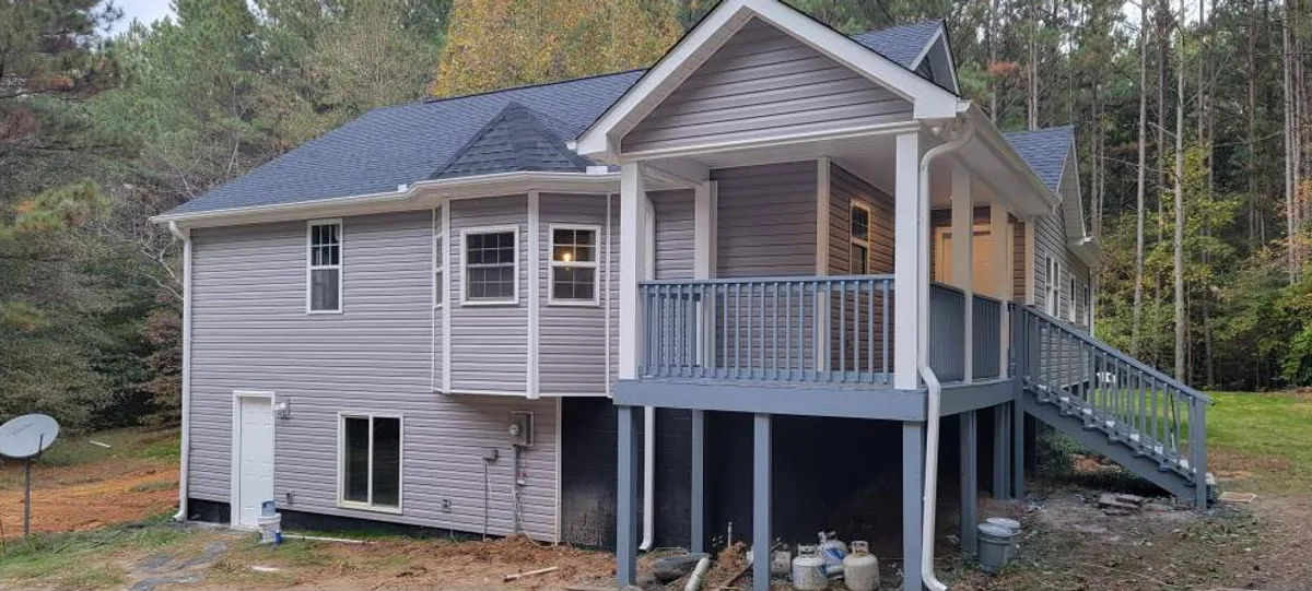 Whole-home remodel exterior with new gray vinyl siding, architectural shingle roof and covered porch