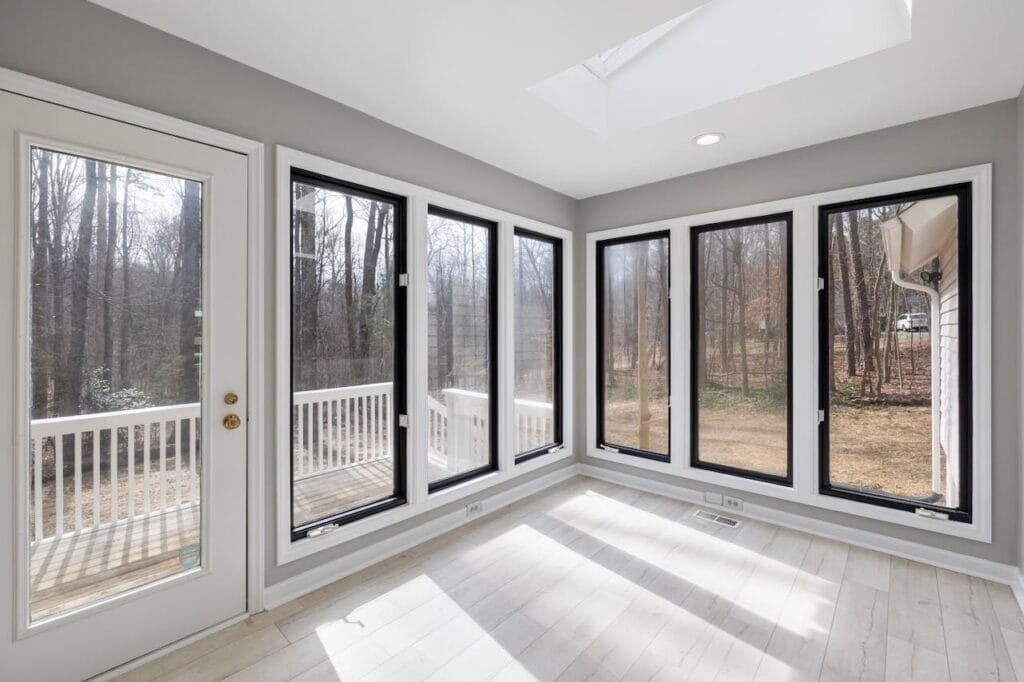 Spacious sunroom with floor-to-ceiling windows offering tranquil forest views.